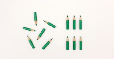 Short green pencils laying on a white background