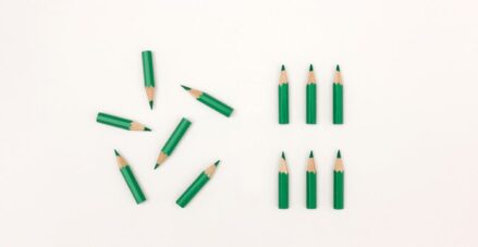 Short green pencils laying on a white background