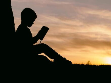 Shilloute of a child reading a book