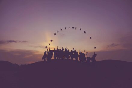 Students on top of a hill celebrating graduation