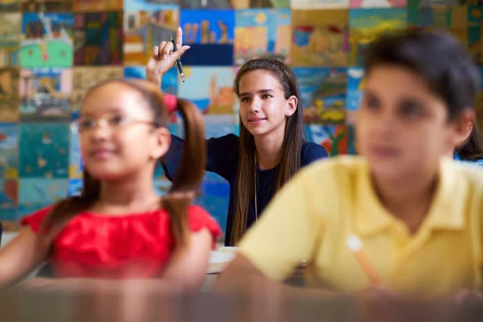 Young female student holding hand up in a class