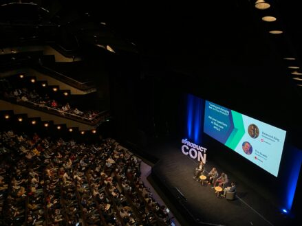 wide shot of a group of people gathered at a conference in an auditorium-style room
