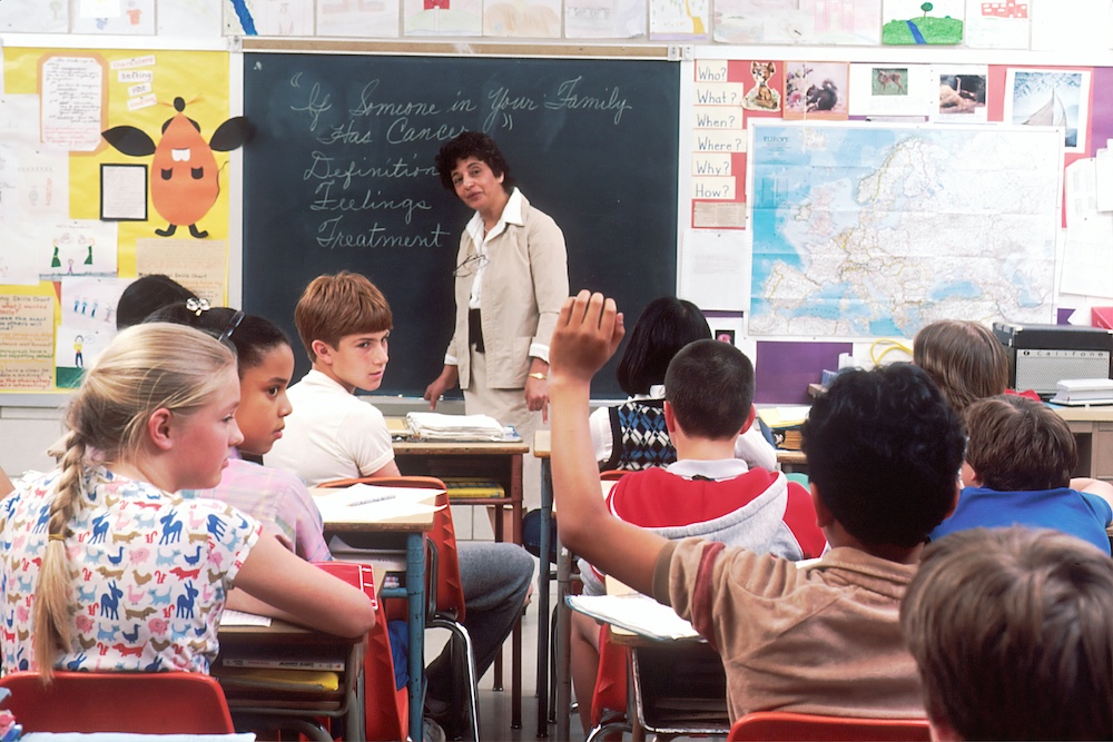 photo of a classroom full of students watching their teacher at the front of the room