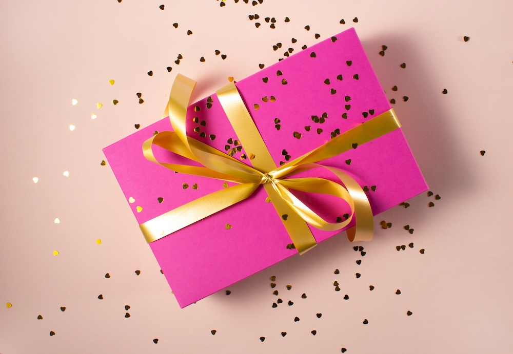 gift wrapped in pink wrapping paper with gold bow attached
